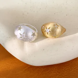 Scherpe detailopname van geborstelde metalen ovale ringen met sterpatronen en zirkonen.