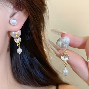 Close-up of elegant pearl tassel stud earrings with gold-tone accents worn by a model