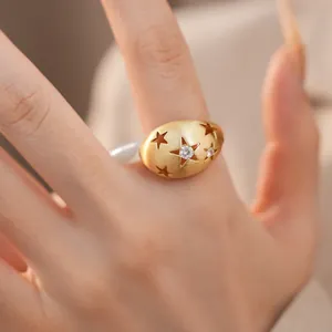 Macrodetail van goudgeborstelde ovale ring met ster en ingelegde zirkoon