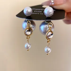 Elegant double pearl drop earrings featuring a gold tassel and sparkling crystal detail.