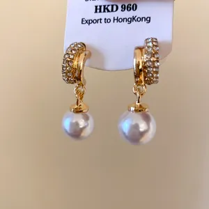 Detailed close-up of gold-plated hoop earrings with crystals and elegant white pearls