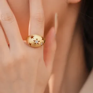 Detailopname van een matgouden ovale ring met uitgesneden sterren en zirkoonsteen