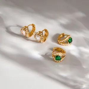 Detailed macro view of gold-plated stainless steel hoop earrings with green zirconia