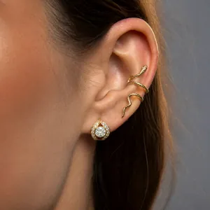 Detailed close-up showing a gold snake-shaped ear cuff and zircon stud earring on a model ear