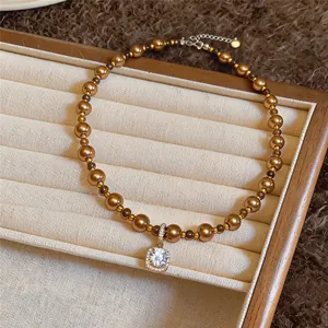 Detailansicht einer bronzefarbenen Perlenkette mit quadratischem Zirkonia-Anhänger im Etui.