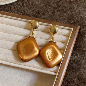 Detailansicht der Vintage-Ohrhänger in Rautenform mit Bernsteinharz und Goldfinish.