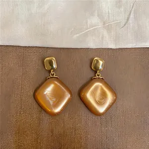 Detailansicht der Vintage-Ohrhänger aus Gold und bernsteinfarbenem Harz in Rautenform