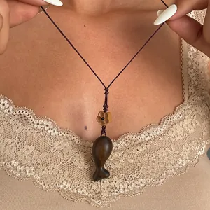 Macro view of vintage ethnic style wooden fish pendant necklace with purple woven rope