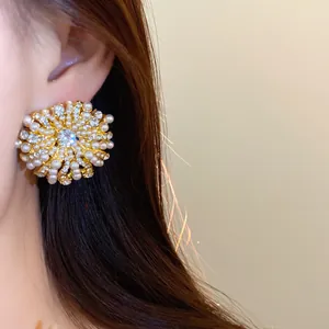 Detailed close-up of a pearl and rhinestone flower earring on a model's ear