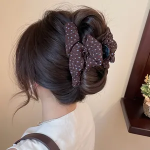 Detail van bruine haarklem met bloemenprint stoffen strik op donkerbruin haar
