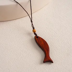 Detailed close-up view of a handcrafted ethnic style wooden fish pendant with woven rope