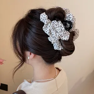 Gedetailleerd beeld van een bloemenstoffen haarklem op een bruine knot haarstijl