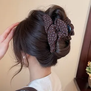 Detail van een bruine bloemenstof haarklem gestyled in een elegante knot kapsel