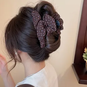 Detailweergave van een bruine haarklem met bloemenprint op een stijlvol kapsel.