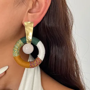 Nahaufnahme eines Retro-Ohrrings mit bunter Baumwollkordel und Harzperle.
