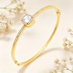 Close-up view of gold-plated bangle with square rhinestone center and spring clasp