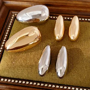 Minimalist polished metal oval stud earrings set in silver and gold finishes for women