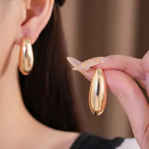 Detail view of oval polished gold stud earrings showing high shine metallic minimalist style