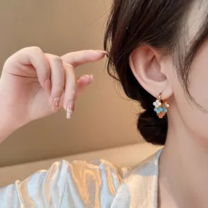 Détail macro de boucles d'oreilles créoles avec fleurs en zircon portées par un modèle