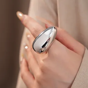 Close-up detail of a large chunky oval silver ring with a high-polish mirror finish
