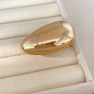 Close-up of golden smooth oval stud earring with high-shine metallic finish