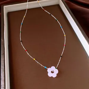 Detail van een kristallen bloemenketting met kleurrijke kralen op een zilveren ketting.