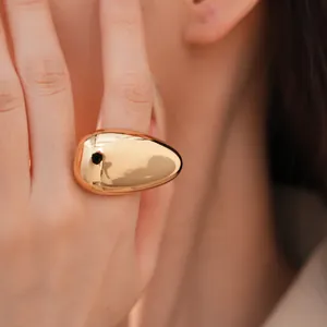 Detailed macro view of an oversized smooth gold oval ring featuring a reflective metallic surface