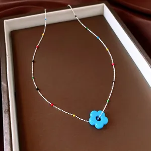 Gedetailleerde opname van kleurrijke kralenketting met een helderblauwe bloemhanger