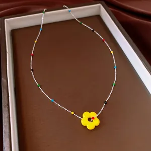 Detailopname van een kleurrijke dopamine halsketting met een heldergele bloemenhanger