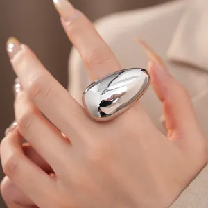Detailed close-up of a minimalist large polished silver oval ring on a woman's finger