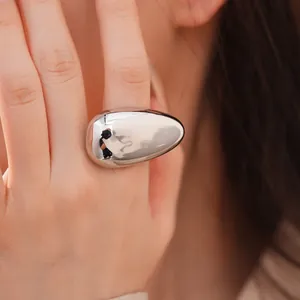 Detailed macro shot of a large oval smooth silver ring with high-gloss reflective finish