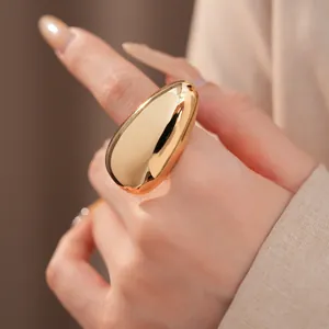 Detailed view of a smooth gold oval ring worn on a finger in minimalist style.