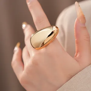 Detailed view of a minimalist smooth gold-finish chunky oval ring on a manicured finger