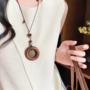 Vista detallada de un collar con colgante de resina étnica sobre un top beige