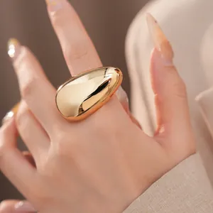 Close-up detail of a minimalist smooth gold oval ring with high-polish metallic finish