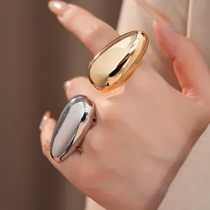 Macro view of two oversized teardrop metallic rings in gold and silver glossy finishes.