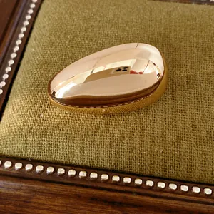 Close-up of a smooth gold teardrop stud earring on an olive green jewelry display.