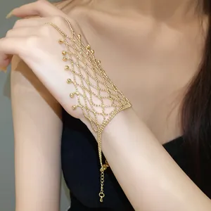 Detail shot of a golden hollow fringe ring-bracelet hand harness on a model's hand.