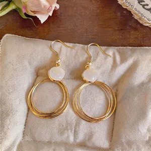 Elegante goldene konzentrische Creolen mit weißem Opal-Cabochon-Detail für modische Frauen