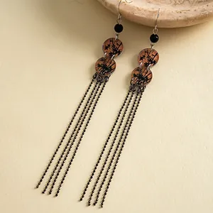 Gros plan de boucles d'oreilles vintage en acrylique avec motifs de bambou et glands noirs
