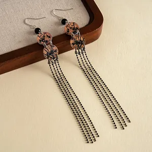 Détail de boucles d'oreilles style cour vintage avec imprimés ronds en acrylique et franges.