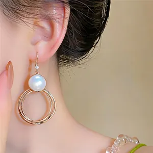 Detailansicht eleganter goldfarbener Hängerohrringe mit einer großen weißen Perle
