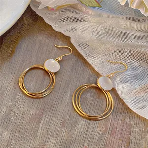 Detailansicht goldener Mehrschicht-Ohrringe mit weißem Edelstein-Akzent.