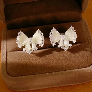 Elegante crèmekleurige strik oorbellen met zirkoon en parels in fluwelen doos