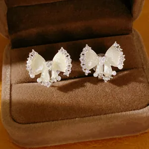 Detailopname van elegante strik-oorclips met zirkoon en parels in een sieradendoosje