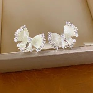 Detail van elegante strik oorklemmen met glanzende zirkonia en witte parels op een box