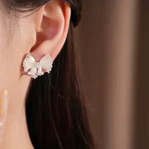 Detailopname van elegante zirkonia strik oorclip met parelaccenten en emaille afwerking.