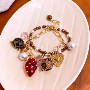 Elegantes zweilagiges Perlenarmband mit Herz- und Erdbeeranhängern im Retro-Luxus-Design.