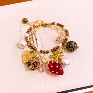 Detailansicht eines charmanten Vintage-Doppelarmbands mit Erdbeer- und Herzanhängern