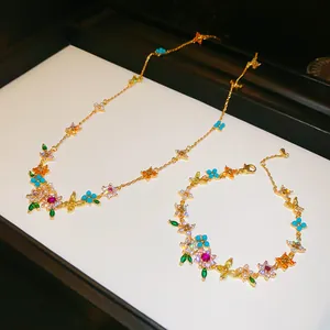Detailed shot of 18k gold-plated jewelry set with colored zircon flower and butterfly motifs.